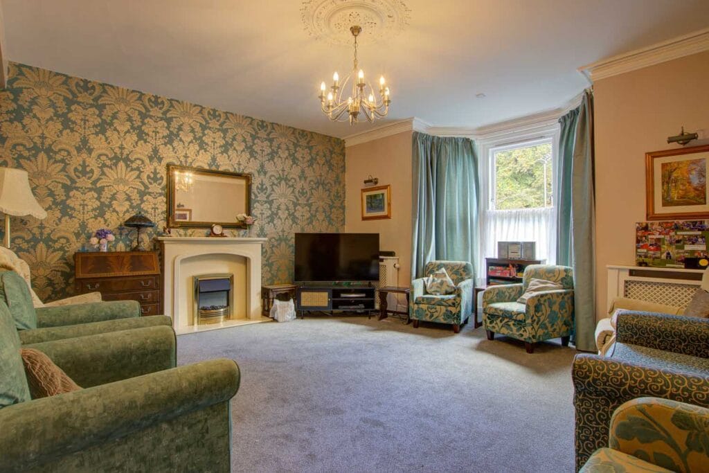 A comfortable lounge at Carntyne with armchairs, a fireplace and a bay window
