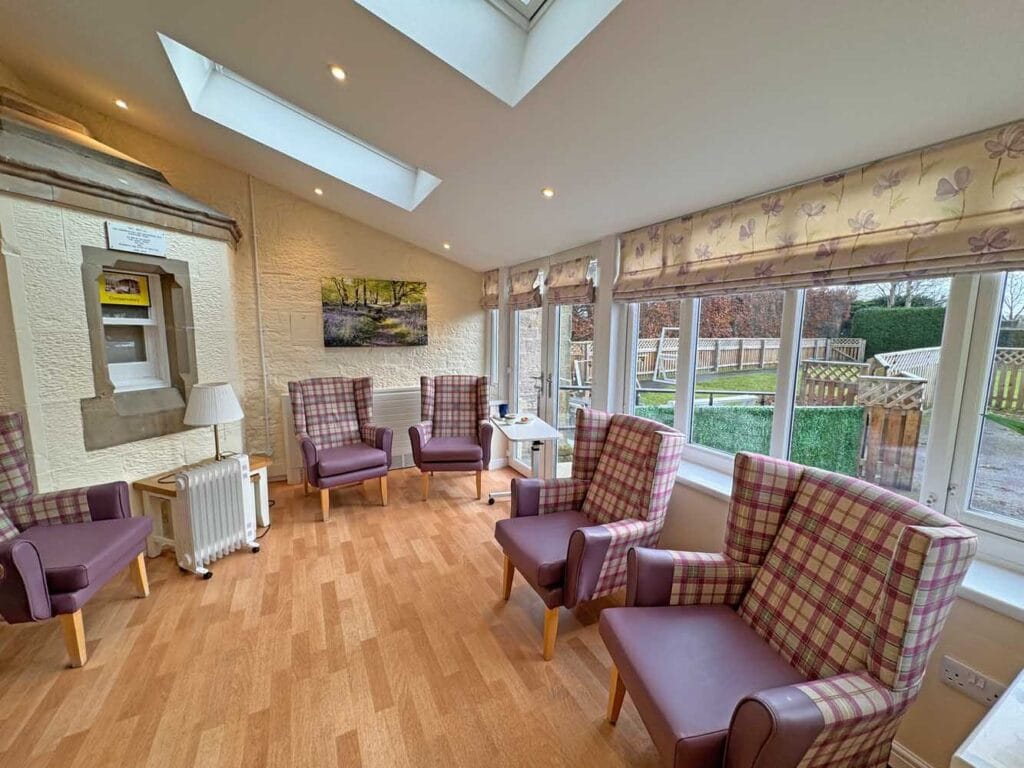 A bright sun lounge at Birch Hill with armchairs beside windows onto the garden